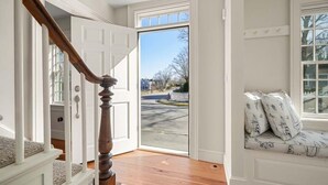 A staircase leading to a door, a bench with patterned cushions, and a view of the outside.