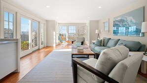 A spacious living room with a large window, a sofa, a coffee table, and a painting on the wall.