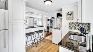 A modern kitchen with white cabinetry, a granite countertop, and a built-in island with bar stools.