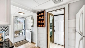 A modern kitchen with white cabinetry, a black countertop, and a built-in wooden shelf with bowls.