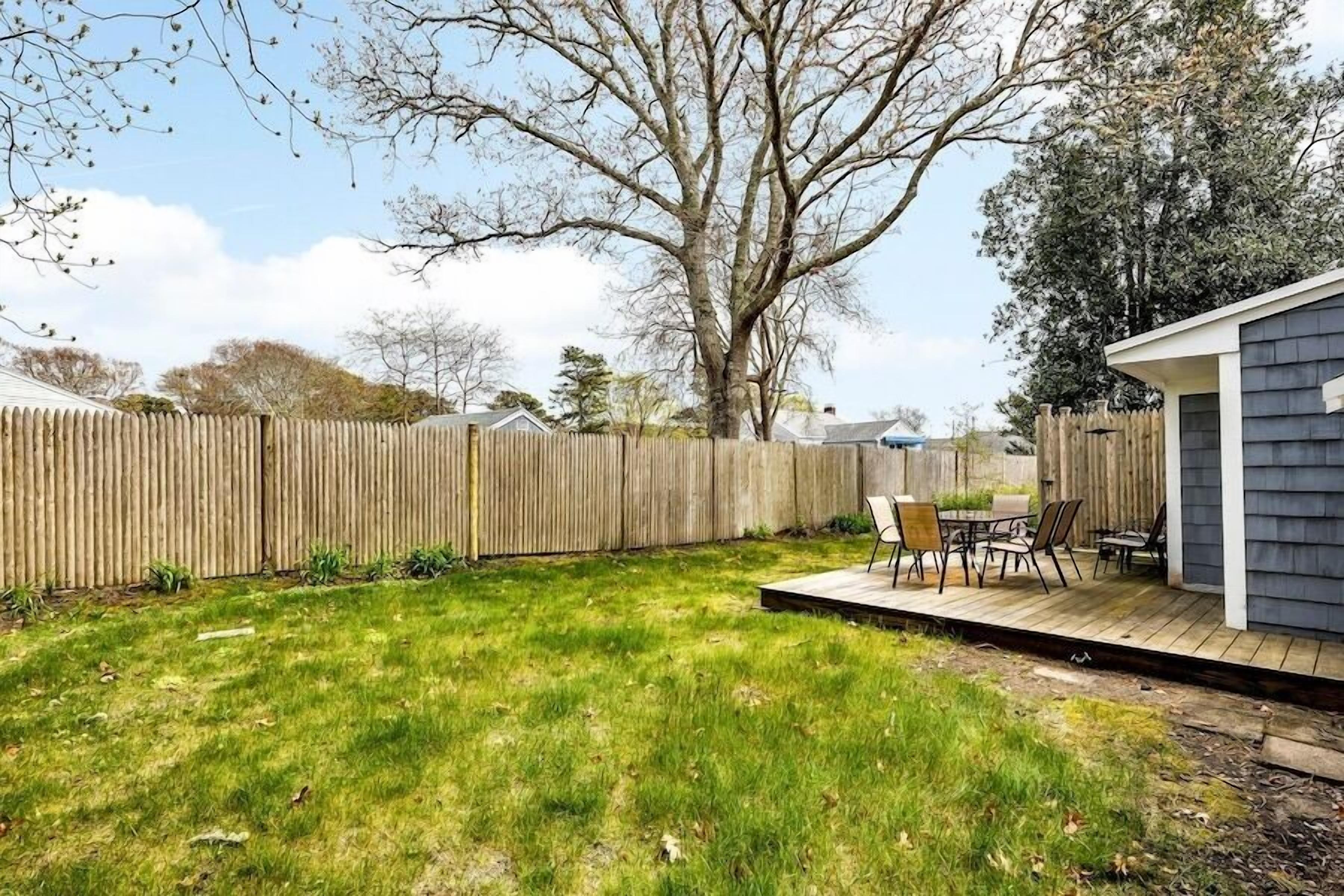 A backyard with a wooden deck, a small patio table, and chairs.