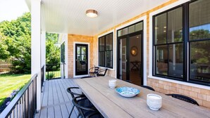A covered patio with a wooden table, chairs, and a bowl. - Dazzling High End Home with Heated Pool, Spa and Guest House RPAM013 (East Dennis)