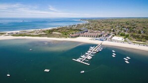 Eine Luftaufnahme einer Küstenregion mit einem Yachthafen, Strand und Wohngebäuden.