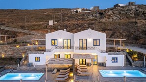 Une villa moderne dotée d’une piscine, d’un espace salon extérieur et d’un escalier en pierre menant à l’entrée.