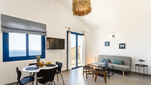 Un salon moderne comprenant un coin repas, un canapé et un téléviseur fixé au mur.