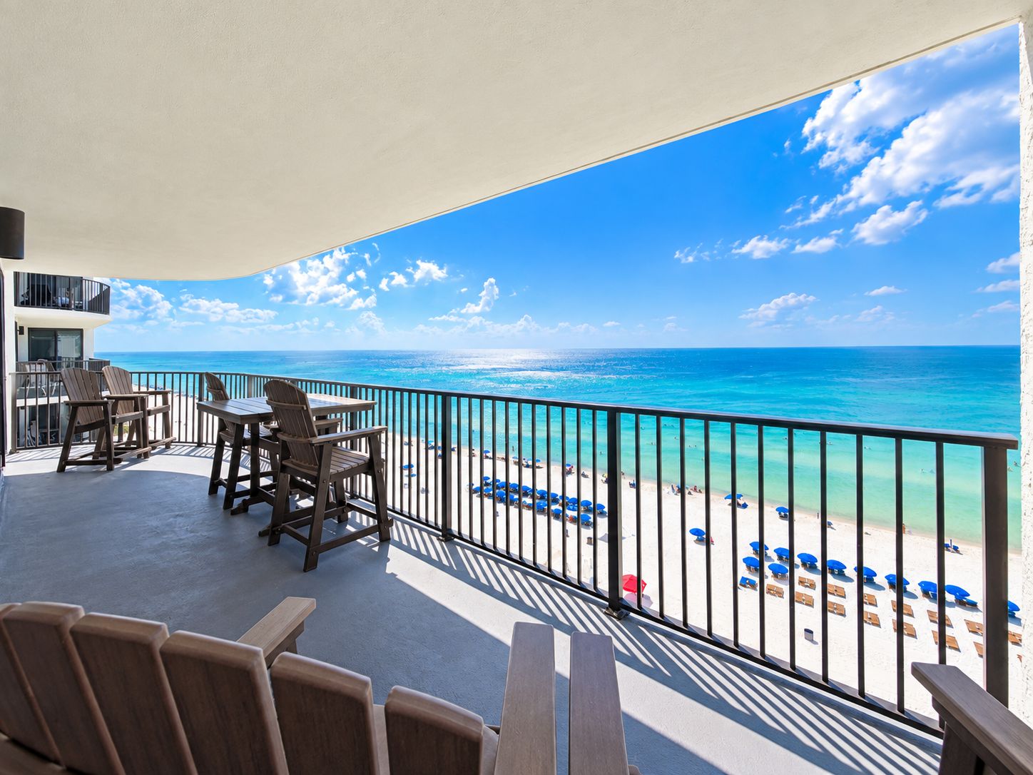 Un balcon avec vue sur la plage, des sièges d’extérieur et une rambarde.