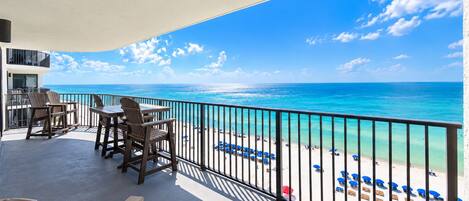 Un balcon avec vue sur la plage, des sièges d’extérieur et une rambarde.