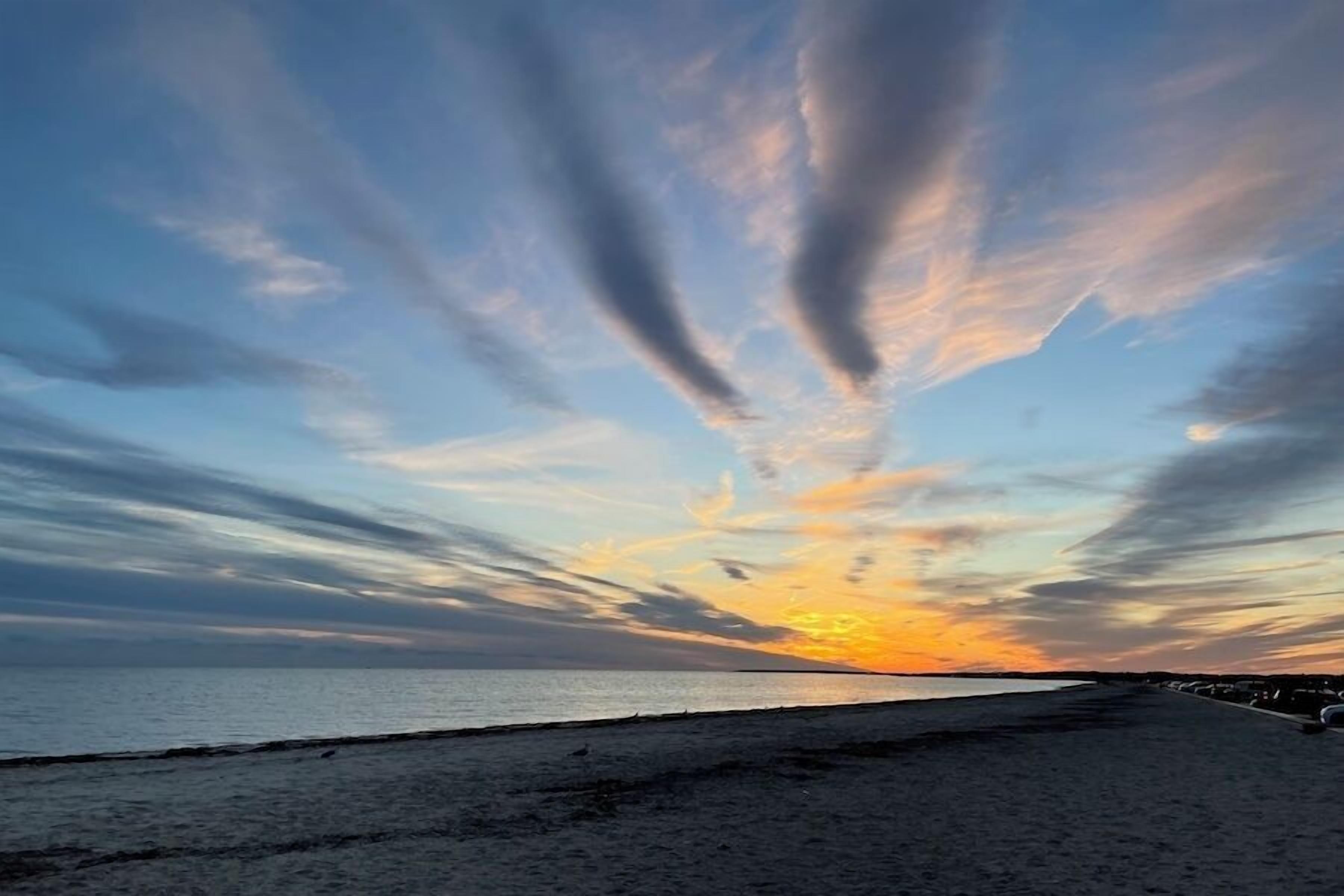 Une plage au coucher du soleil, avec des nuages.