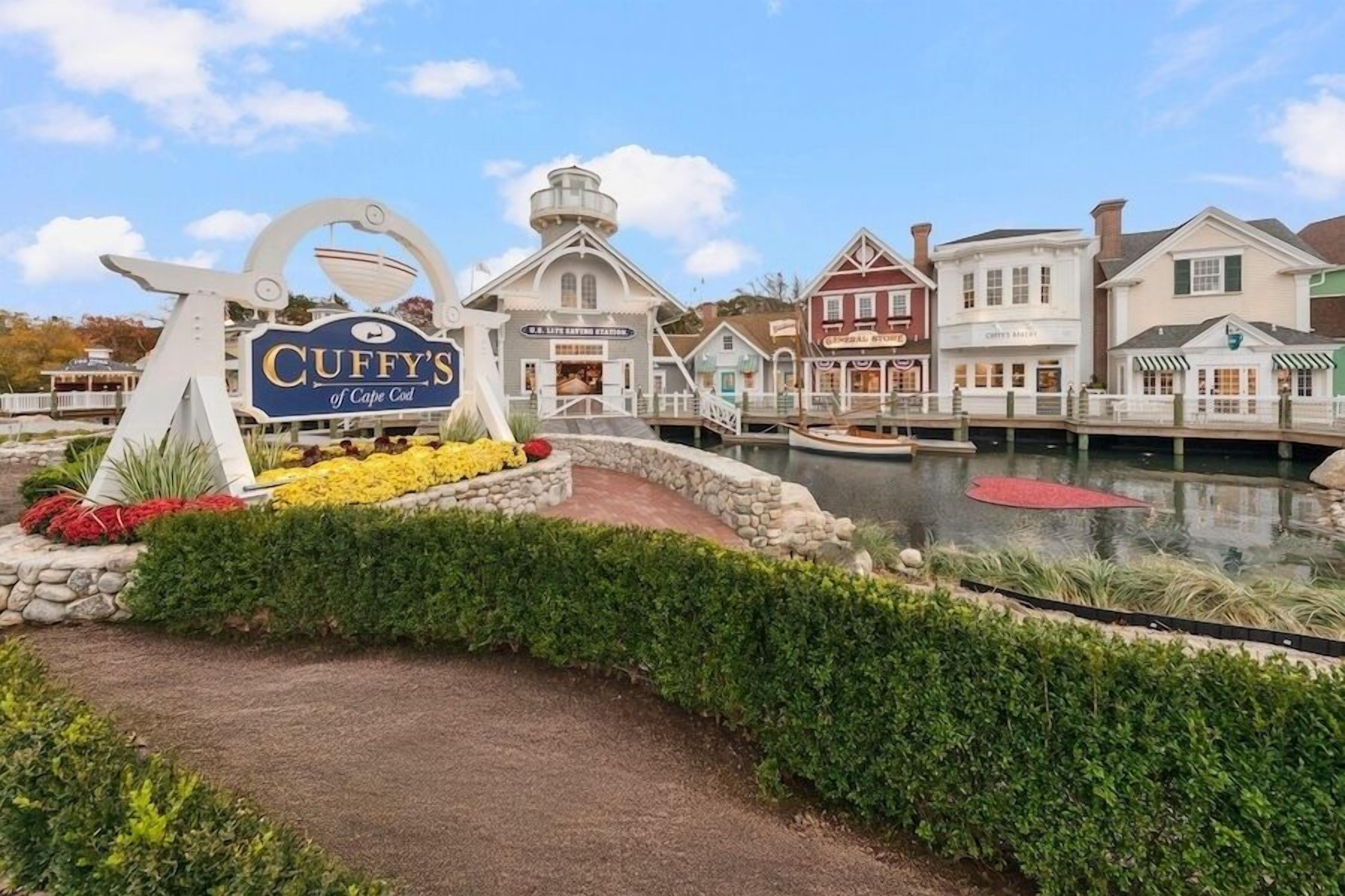 Una zona frente al agua con un letrero de Cuffy's de Cape Cod, una estación de salvamento de G.S. y varios edificios con estilos arquitectónicos diferentes.