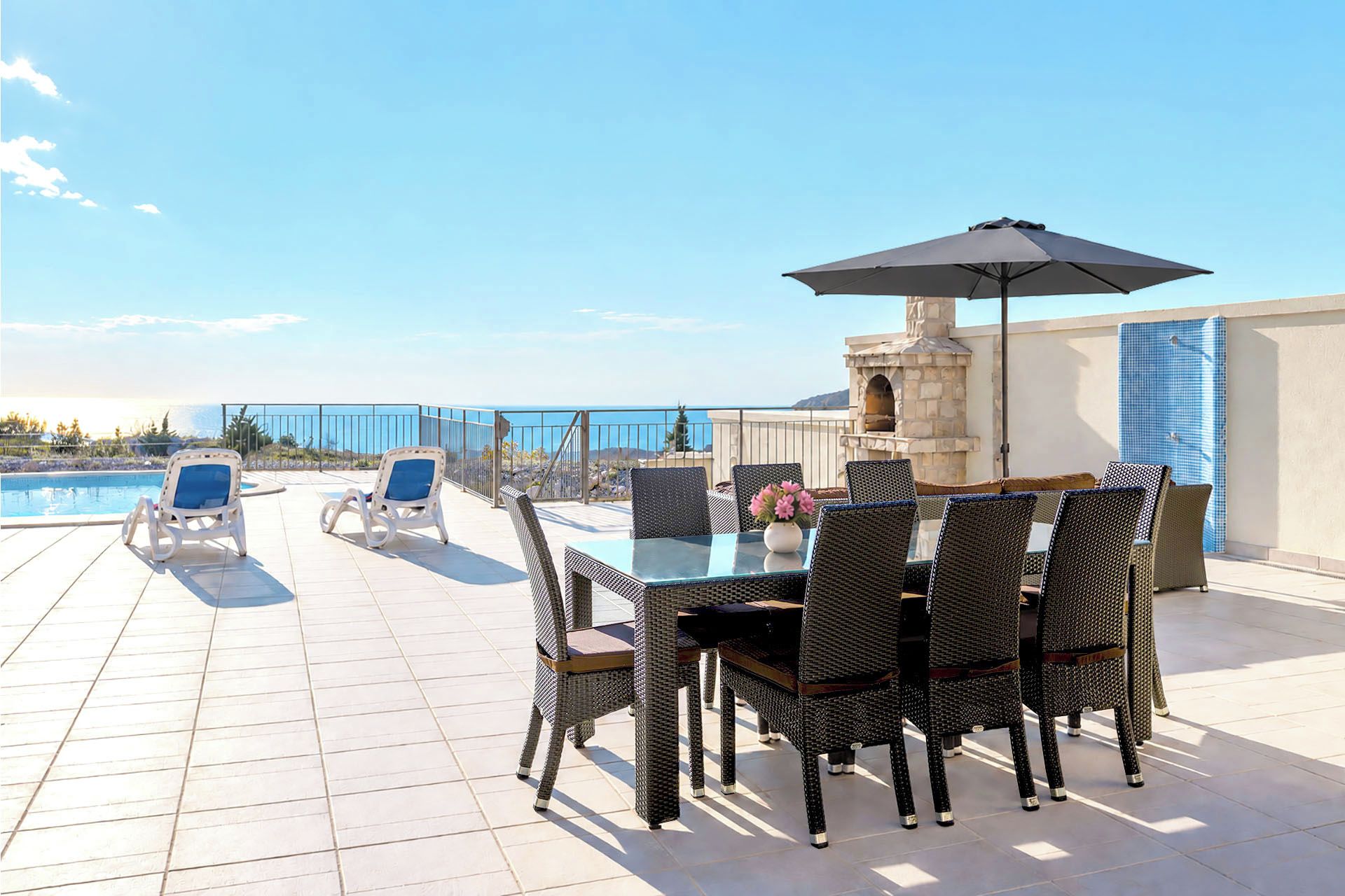 A rooftop terrace with a pool, lounge chairs, and a dining area with wicker furniture and a table.