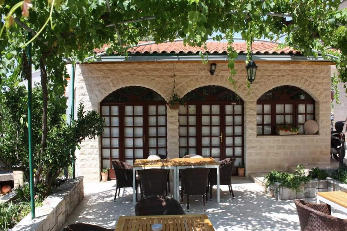 An outdoor patio with a stone wall, arched windows, and a wooden table.