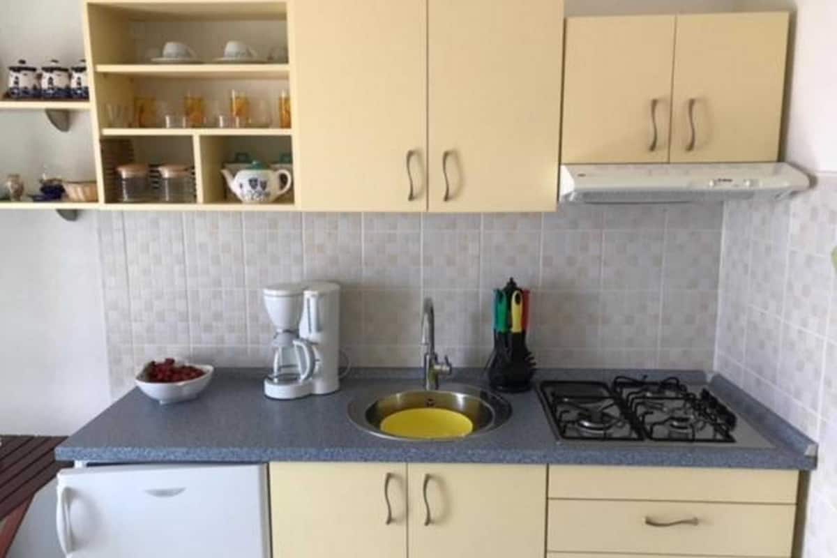 A compact kitchen with a sink, stove, and a coffee maker.