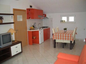 A compact living space with a kitchenette, dining area, and a TV on a stand. - Apartments Paloc (Bol)