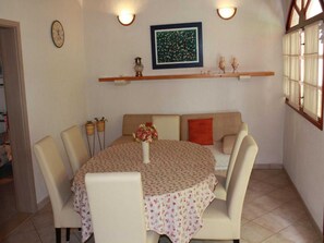 A dining area with a round table, chairs, a vase with flowers, a clock, a framed picture, and a shelf with decorative items. - Apartments Paloc (Bol)