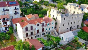 Zona residencial con edificios de varios pisos, techos de tejas rojas y abundante vegetación.