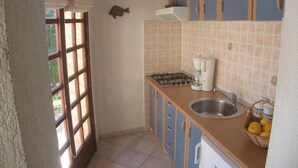 Una cocina compacta con estufa a gas, cafetera y lavabo.