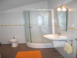 Un baño con cabina de ducha de vidrio, un lavabo, un inodoro y un espejo.