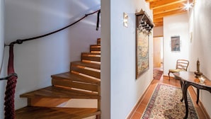 A wooden staircase with a rope handrail, a dining area with a table and chairs, and a patterned rug on the floor. - Ca' Pinina (Lugano)