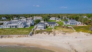 Una zona residencial costera con varias casas, una playa de arena y una vista despejada del océano.