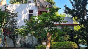 A white building with a thatched roof, surrounded by lush greenery and a small pool. - casademarthayjaimealjuntoalrioveracruz (Veracruz)