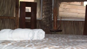 A bed with a white towel, a wooden chair, and a rustic wall with a window. - casademarthayjaimealjuntoalrioveracruz (Veracruz)