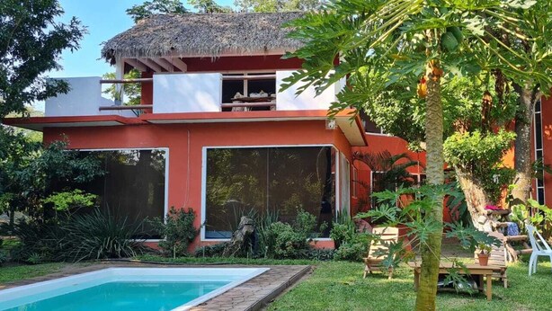 A modern house with a pool, surrounded by lush greenery and a thatched roof structure. - casademarthayjaimealjuntoalrioveracruz (Veracruz)