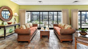 A spacious living room with two wicker sofas, a coffee table, and a large mirror.