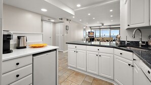 A modern kitchen with white cabinets, a black countertop, and a dishwasher.