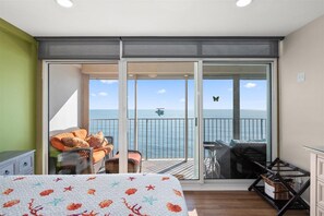 Enjoy a room with a balcony offering a sea view, a comfortable bed, and a convenient nightstand with a lamp.