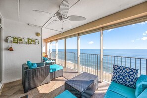 Enjoy ocean views from this furnished balcony with sofas, a table, and ceiling fan.