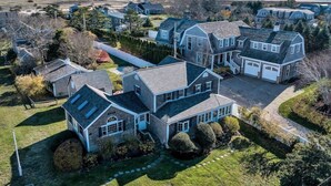 A large, multi-story house with a spacious driveway and a well-maintained lawn. - Private Beach Front Chatham Rental Close To Everything RPAM054 (Chatham)