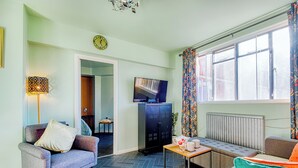 Un salon avec un canapé, un fauteuil et un téléviseur posé sur un meuble.