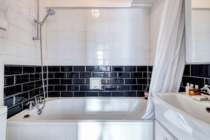 A modern bathroom with a large bathtub, a shower, and a vanity with a mirror. - Hardwood Home (London)
