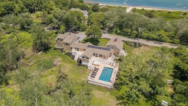 An aerial view of a large house with a swimming pool, surrounded by dense greenery and a beach. - Elevate Your Cape Stay: Chatham Luxury with Pool & Beach RPAM026 (Chatham)
