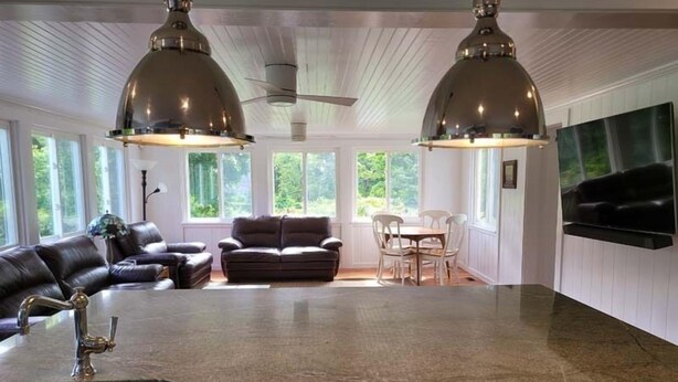 Un vaste espace de vie doté d’un grand îlot central, de deux ventilateurs de plafond et d’un téléviseur à écran plat fixé au mur.