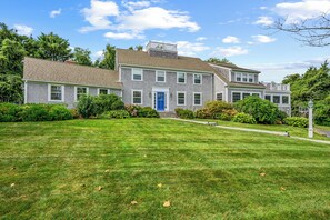 A two-story house with a well-maintained lawn and a blue door.