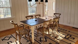Une salle à manger avec une table en bois foncé, six chaises en bois et un tapis à motifs.