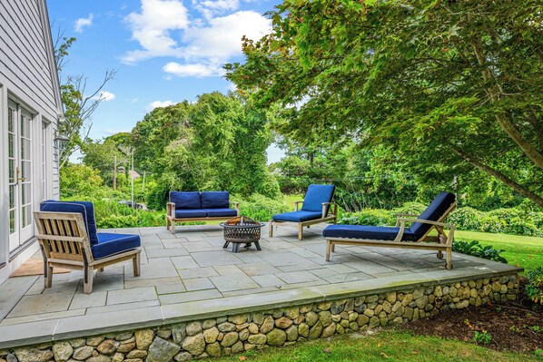 A patio with outdoor furniture, a fire pit, and a stone wall.