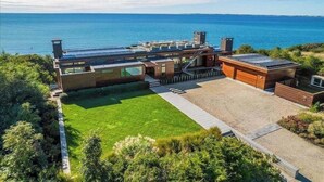 Une maison moderne dotée d’une grande pelouse et offrant une vue sur la mer.