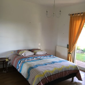 A bedroom with a bed, a bedside table, a lamp, and a window with curtains.