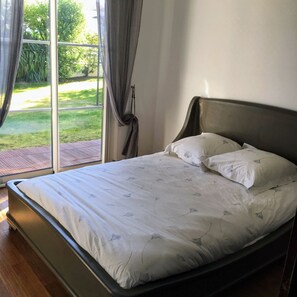 Une chambre à coucher avec un lit, des rideaux et une vue sur la verdure.