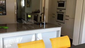 Una cocina moderna con armarios blancos, encimera negra y una silla amarilla.