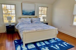 Een slaapkamer met een bed, twee nachtkastjes en een groot raam.