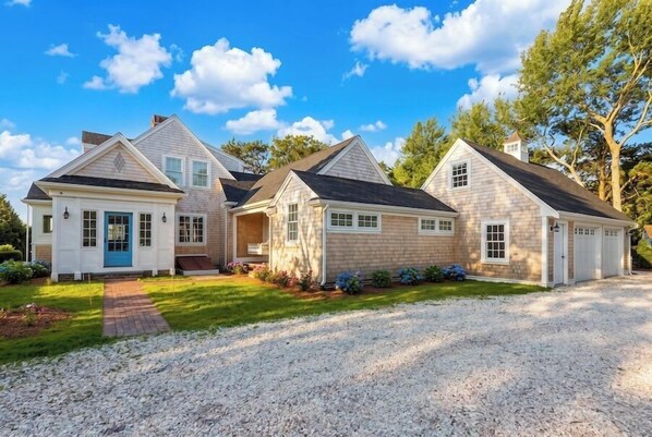 A three-story house with a gravel driveway, a front porch, and a garage.