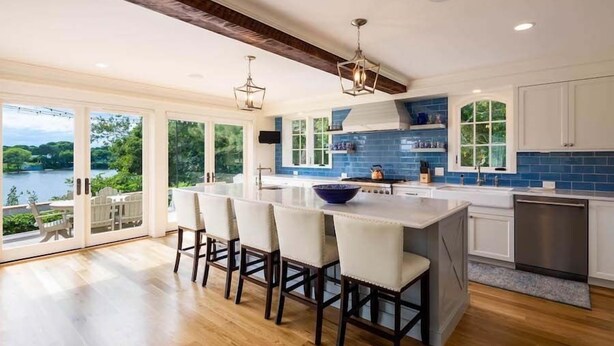 Una cocina moderna con una isla grande, taburetes de bar y vistas a un lago.