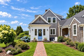 A two-story house with a front porch, a brick pathway, and a well-maintained garden.