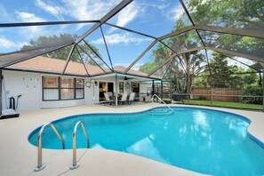 A swimming pool with a covered patio area, a dining table, and chairs. - Exceptional Pool Home in Vero Beach (Vero Beach)