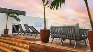 A terrace with wooden steps, lounge chairs, and potted plants against a sunset sky. - 5 Blocks to Beach | Icono Oceanview Pool & Hot Tub (Playa del Carmen)