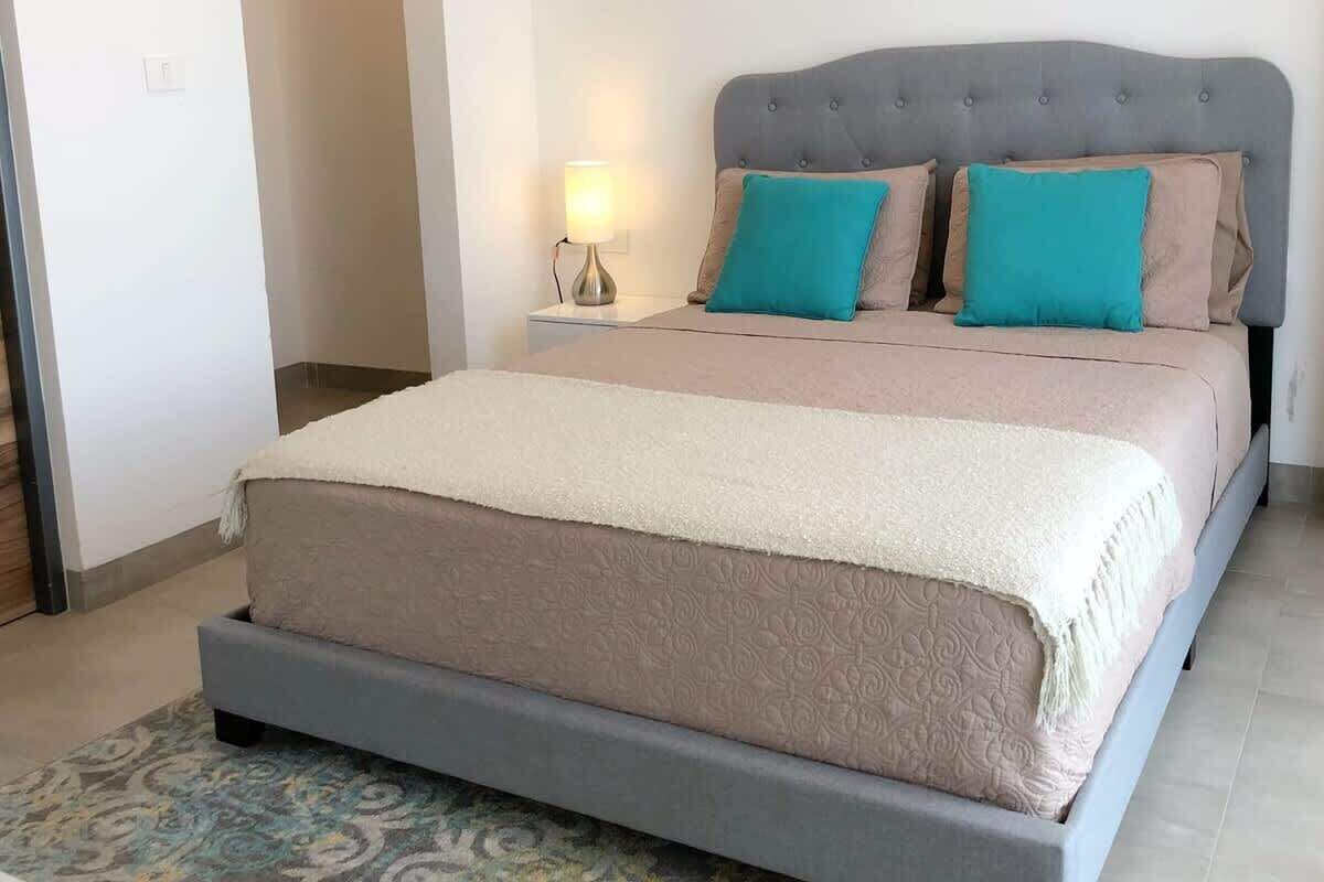 A bedroom with a bed, a nightstand, and a lamp.