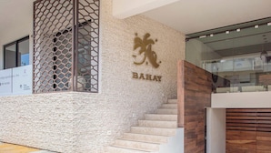 A staircase leading to a room with a textured wall and a logo. - Oceanview Rooftop Pool, Gym & 1 Block to 5th Ave (Playa del Carmen)